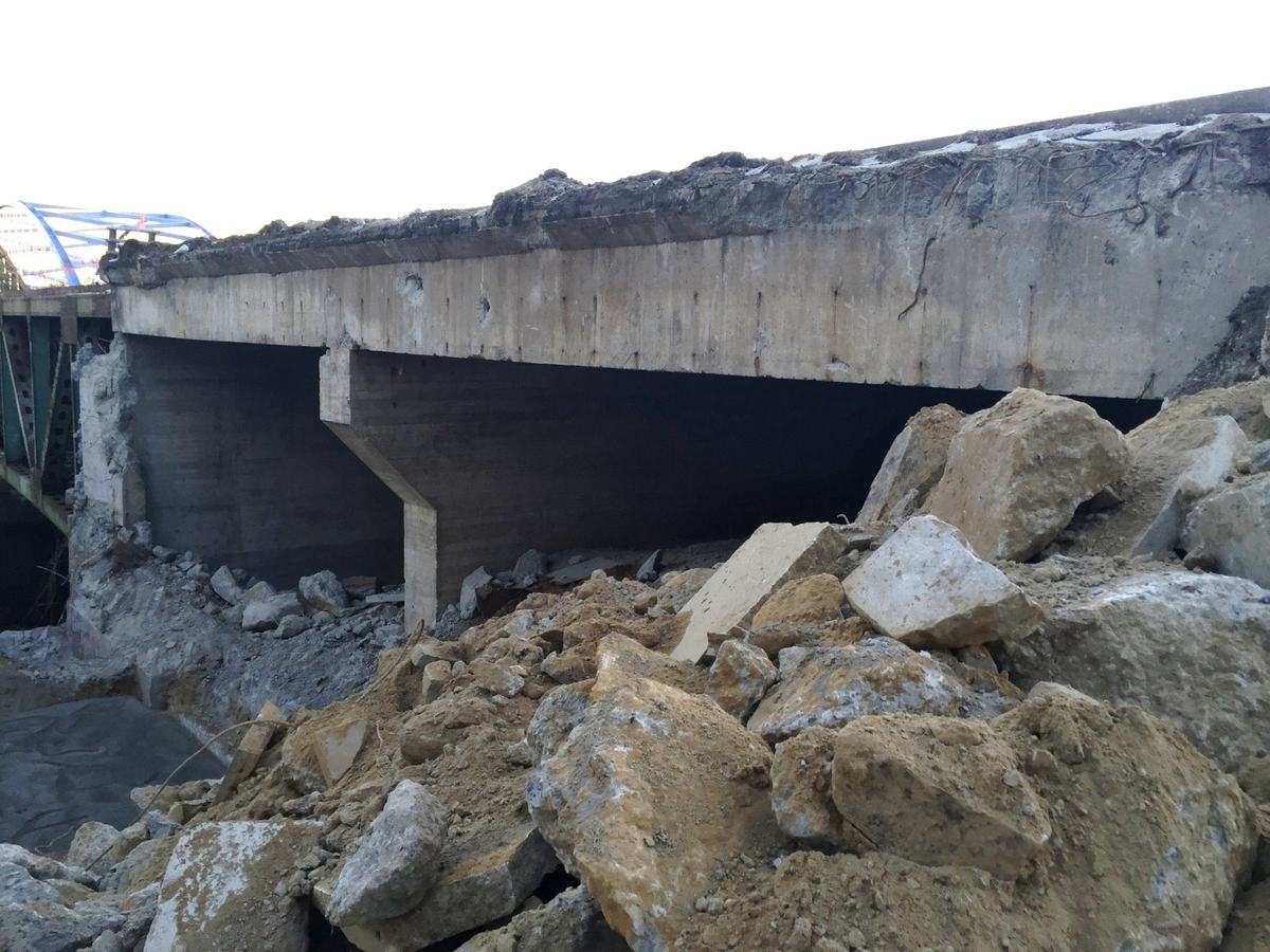 Broken concrete slabs piled under a partly demolished concrete structure